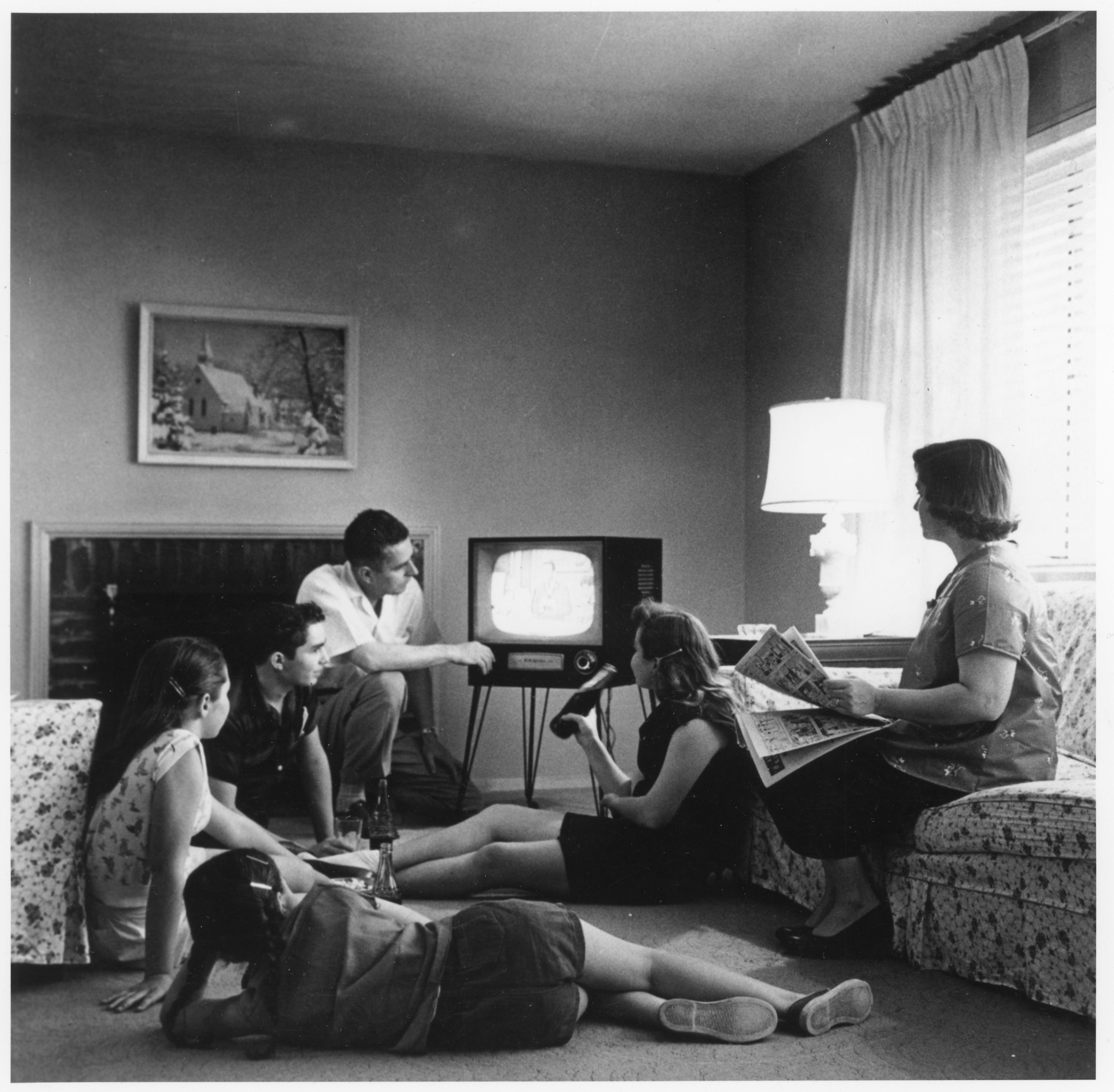 A black-and-white photograph of a family of five watching television in a living room, about 1958.